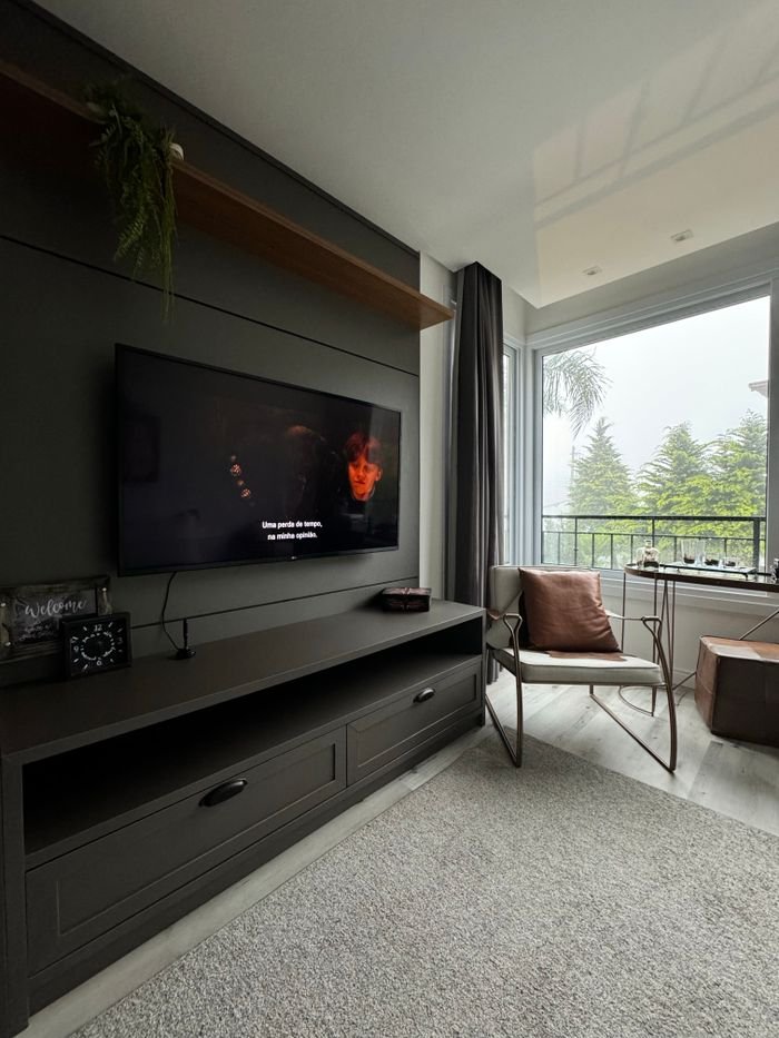 Stylish living room interior with TV and view of greenery through the balcony.